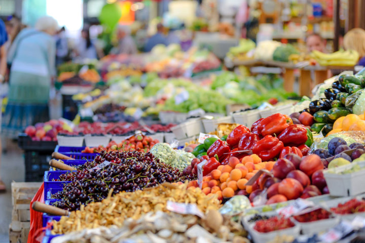 A vibrant outdoor market with various fruits and vegetables on display.