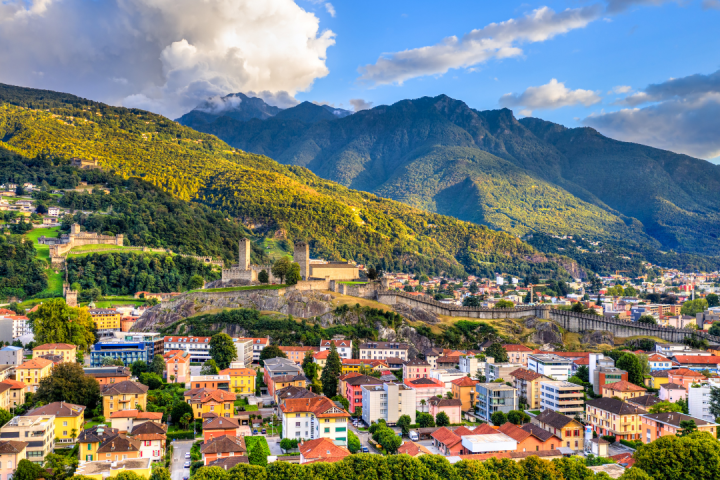 Colorful town with castle and mountains under blue sky in Bellinzona, Switzerland.