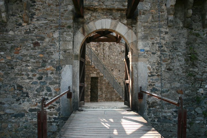 Old stone castle entrance with wooden drawbridge and archway.