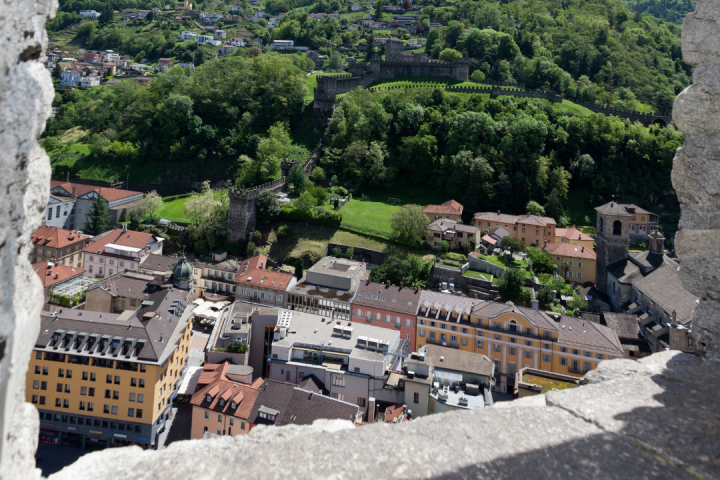 View of a town with colorful buildings, trees, and a green hillside from a stone window.